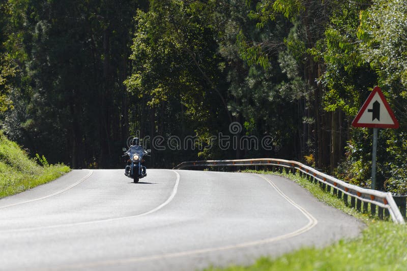 Biker on a custom classic motorcycle rides down the road, road traffic royalty free stock photo