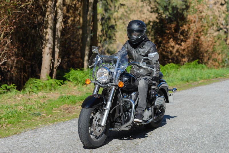 Biker on a custom classic motorcycle rides down the road, road traffic royalty free stock photo