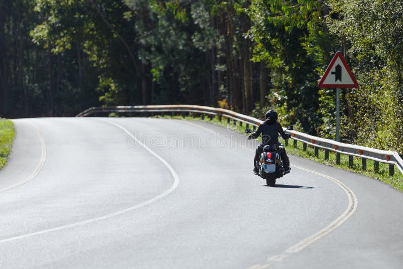 Biker on a custom classic motorcycle rides down the road, road traffic royalty free stock photography