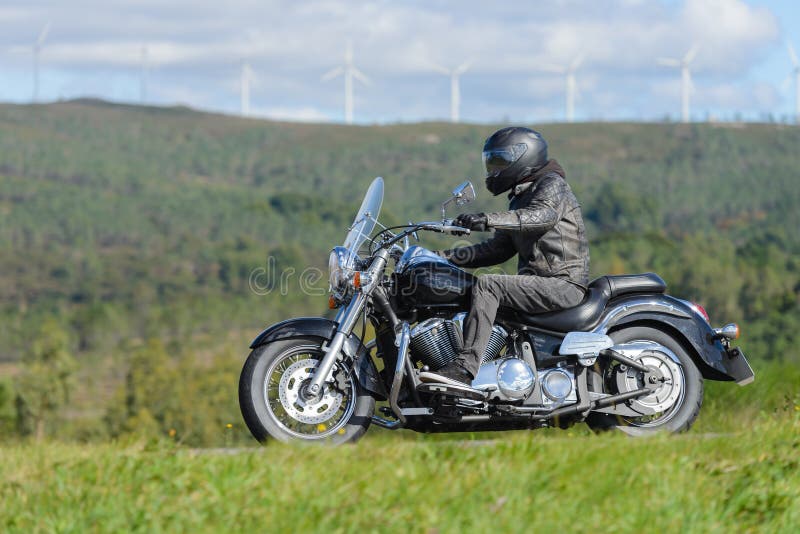 Biker on a custom classic motorcycle rides down the road, road traffic royalty free stock images