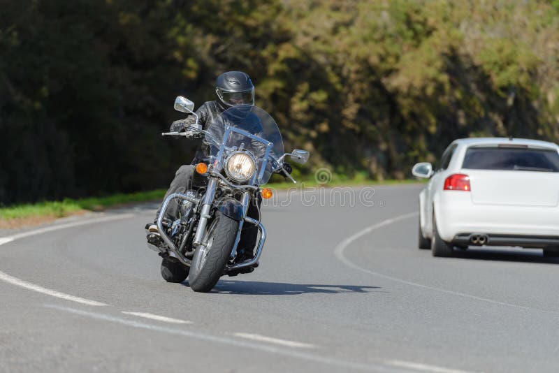 Biker on a custom classic motorcycle rides down the road, road traffic royalty free stock photography
