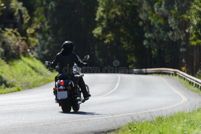 Biker on a custom classic motorcycle rides down the road, road traffic stock photo