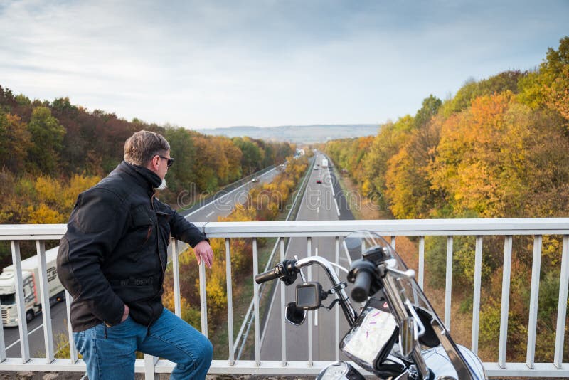 Biker with motorcycle looks on highway