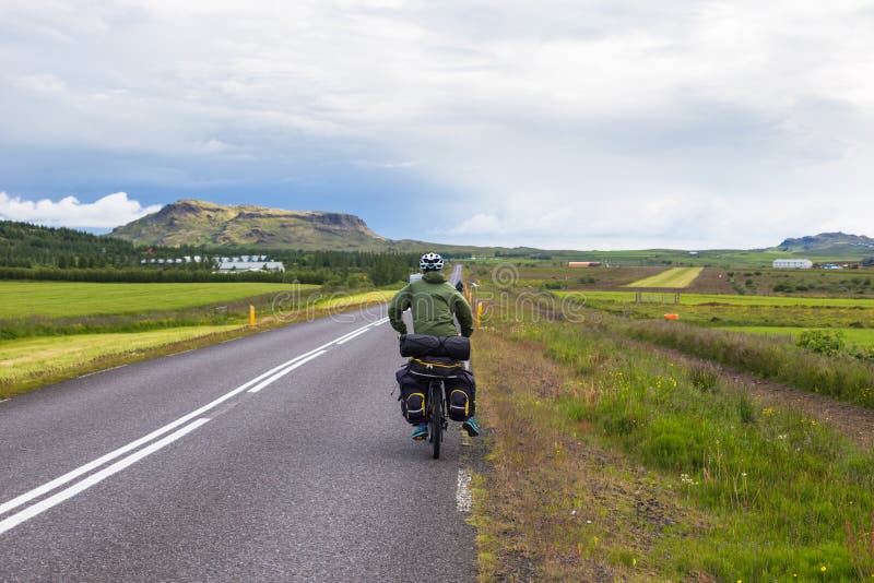 Biker rides on road at sunny summer day in Iceland