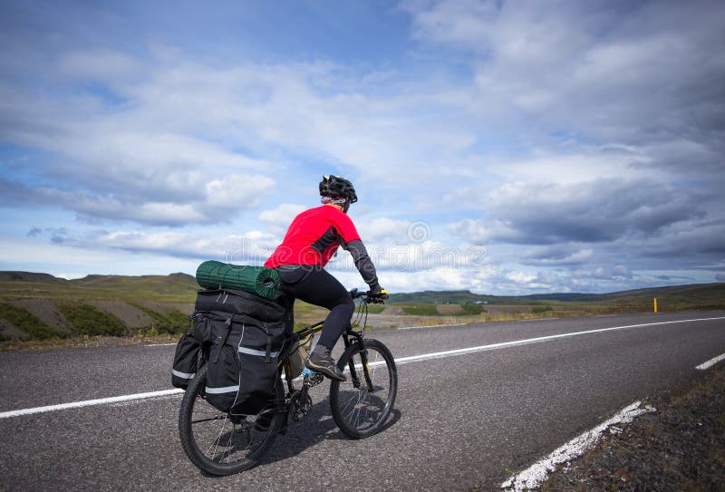 Biker rides on road at sunny summer day in Iceland. Travel and sport picture