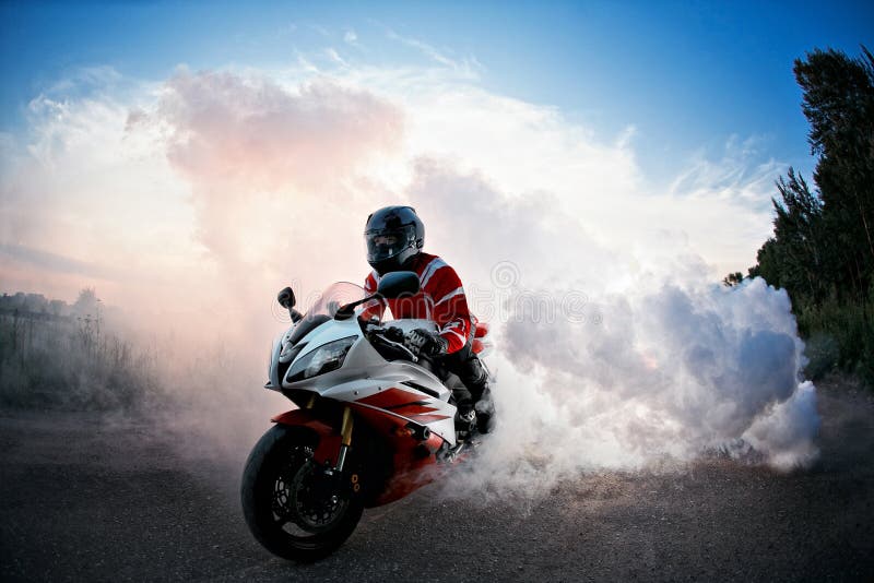 Biker staying on bike road with smoke of the tire, burn out in the moto show. the Sunset royalty free stock photo Biker staying on bike road with smoke of the tire, burn out in the moto show. the Sunset royalty free stock photo