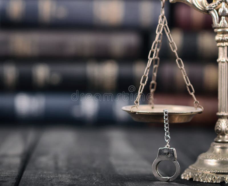 Bilancia della giustizia e manette su un fondo di legno nero fotografia stock Bilancia della giustizia e manette su un fondo di legno nero fotografia stock