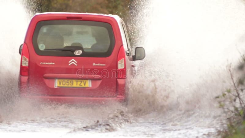 Bilar som kör genom översvämmad väg