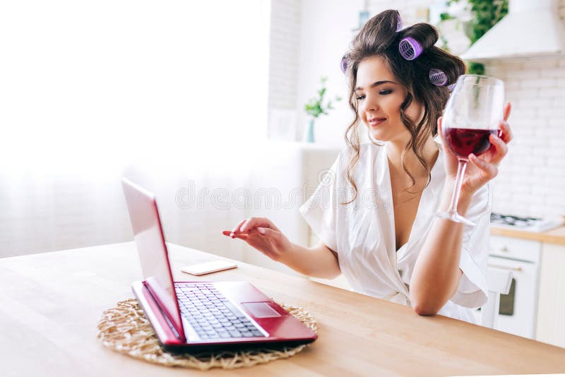 Bild av den hållande ögonen på filmen för härlig hushållerska på bärbar dator- och drinkvin i kök Arbete hemma Oförsiktig hemmafr fotografering för bildbyråer Bild av den hållande ögonen på filmen för härlig hushållerska på bärbar dator- och drinkvin i kök Arbete hemma Oförsiktig hemmafr fotografering för bildbyråer