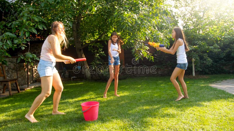 Bild av den lyckliga gladlynta familjen som spelar i tr?dg?rdtr?dg?rden Plaskande vatten f?r folk med vattenvapen och tr?dg?rdsla royaltyfri fotografi Bild av den lyckliga gladlynta familjen som spelar i tr?dg?rdtr?dg?rden Plaskande vatten f?r folk med vattenvapen och tr?dg?rdsla royaltyfri fotografi