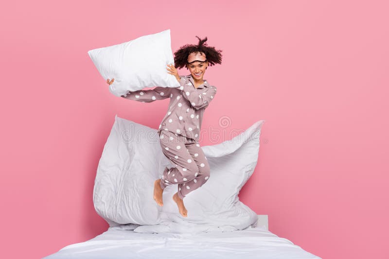 Photo of funky excited lady wear pajama rising pillow jumping high isolated pink color background. Photo of funky excited lady wear pajama rising pillow jumping high isolated pink color background.