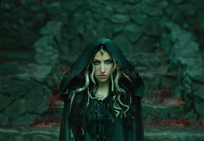 Image of Gorgon Medusa, braid hair and gold snakes, close-up portrait. Gothic make-up in green shades. Background of wild stones. Long black claws and a predatory look. Image of Gorgon Medusa, braid hair and gold snakes, close-up portrait. Gothic make-up in green shades. Background of wild stones. Long black claws and a predatory look