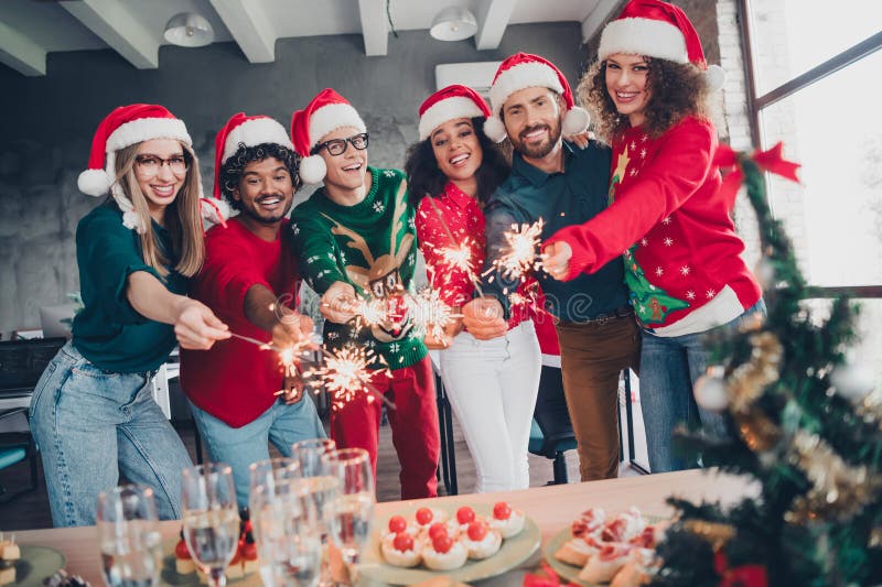 Bild av optimistiska vänner på nyår, fula kläder firar företagspartiets xmas-atmosfär inomhus royaltyfria foton