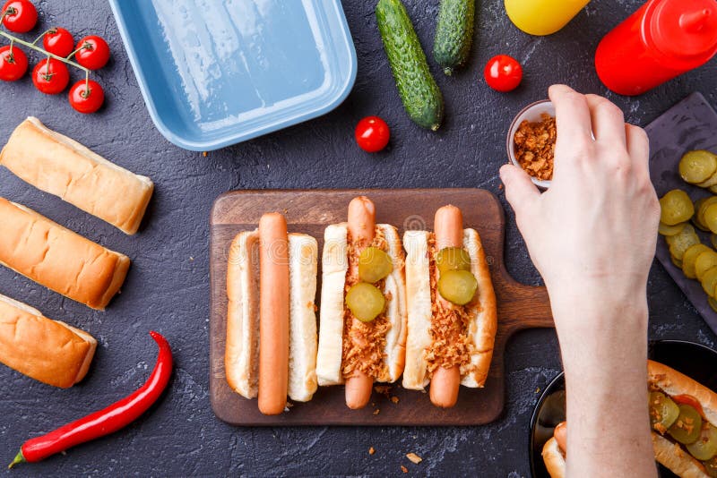 Bild från ovannämnt av mannen som gör hotdogs på skärbräda på tabellen med korvar arkivfoto Bild från ovannämnt av mannen som gör hotdogs på skärbräda på tabellen med korvar arkivfoto