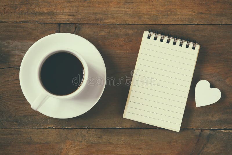 Bild för bästa sikt av den tomma anteckningsboken bredvid koppen kaffe tappning som filtreras och tonas royaltyfri foto
