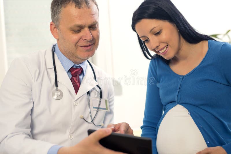 Bild för ultraljud för gynekologdoktorsvisning på den digitala minnestavlan till gravida kvinnan royaltyfri fotografi Bild för ultraljud för gynekologdoktorsvisning på den digitala minnestavlan till gravida kvinnan royaltyfri fotografi