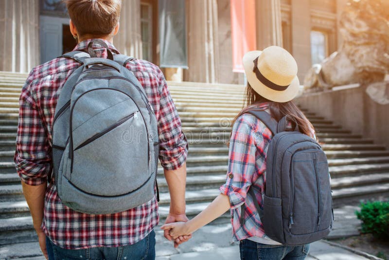 Bild von den jungen Touristen, die vor Treppe stehen Sie halten sich ` s Hände Reisende tragen rocksacks auf ihrem lizenzfreies stockfoto Bild von den jungen Touristen, die vor Treppe stehen Sie halten sich ` s Hände Reisende tragen rocksacks auf ihrem lizenzfreies stockfoto