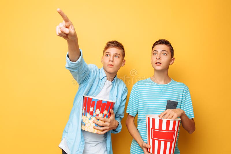 Bild von zwei regte schöne Jugendliche, die Kerle auf, die einen interessanten Film aufpassen und Popcorn auf einem gelben Hinter stockbilder Bild von zwei regte schöne Jugendliche, die Kerle auf, die einen interessanten Film aufpassen und Popcorn auf einem gelben Hinter stockbilder