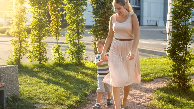 Bilden av den lyckliga unga modern med 3 år gammal liten sonspela och spring på barnlekplatsen på parkerar royaltyfri fotografi Bilden av den lyckliga unga modern med 3 år gammal liten sonspela och spring på barnlekplatsen på parkerar royaltyfri fotografi