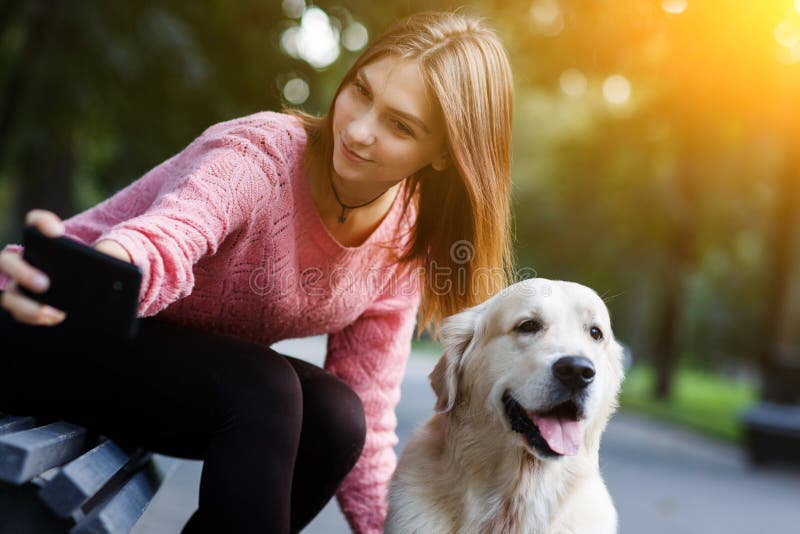 Bilden av kvinnan på selfie för bänkdanande med hunden i sommar parkerar royaltyfria bilder Bilden av kvinnan på selfie för bänkdanande med hunden i sommar parkerar royaltyfria bilder