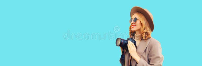 Bilder av elegant, glad, leende kvinnfoto med digitalkamera som tar bilder med rund hatt brun rock på blå