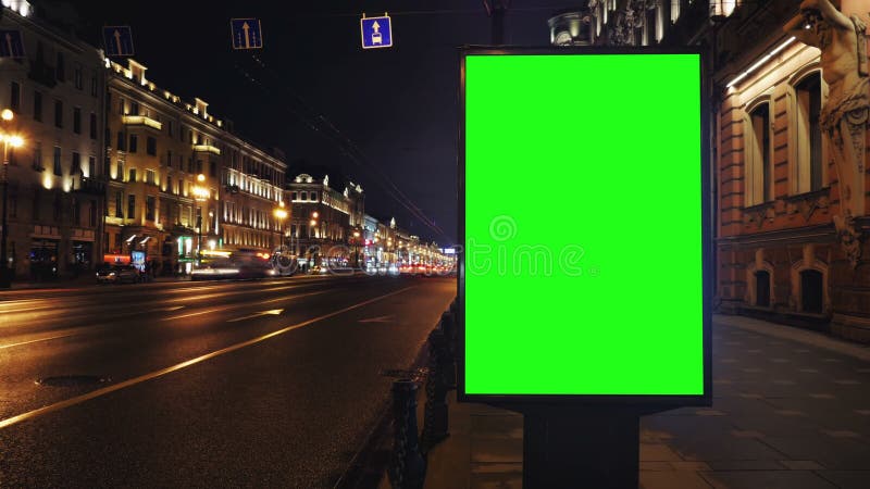 A Billboard with a Green Screen on a Busy Night Street