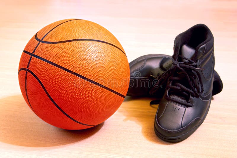 Photo of one basket ball and sneakers in a wooden floor. Photo of one basket ball and sneakers in a wooden floor