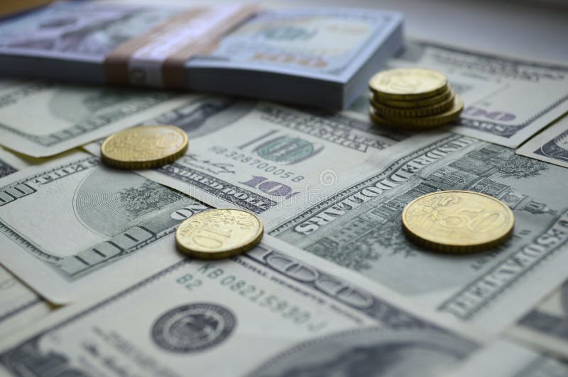 Billetes de banco dispersados de 100 dólares de EE. UU. y monedas del euro fotos de archivo libres de regalías Billetes de banco dispersados de 100 dólares de EE. UU. y monedas del euro fotos de archivo libres de regalías