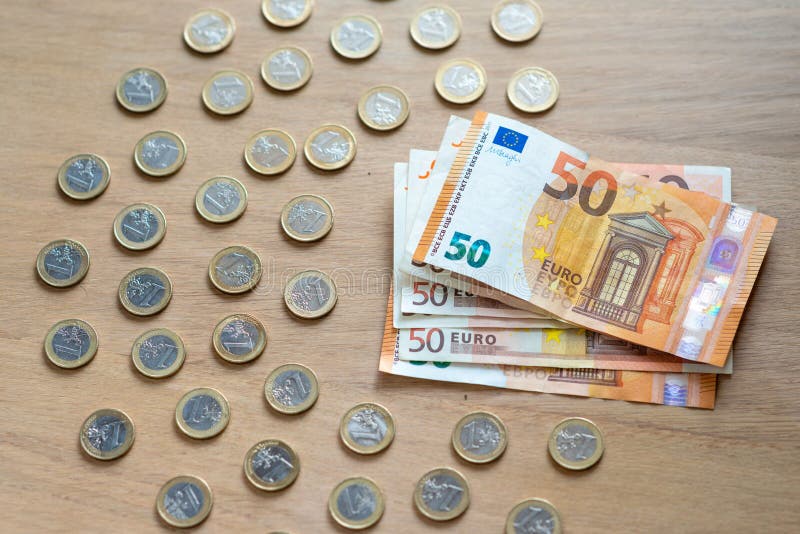 50 billetes de banco euro y monedas de 1 euro en un fondo de madera ligero imágenes de archivo libres de regalías 50 billetes de banco euro y monedas de 1 euro en un fondo de madera ligero imágenes de archivo libres de regalías