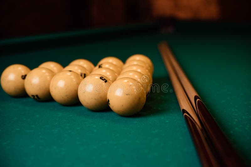 Billiard Cues and Pyramid of Yellow Pool Balls on Green Billiard Table