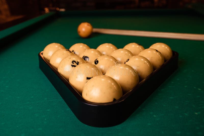 Billiard Cues and Pyramid of Yellow Pool Balls on Green Billiard Table