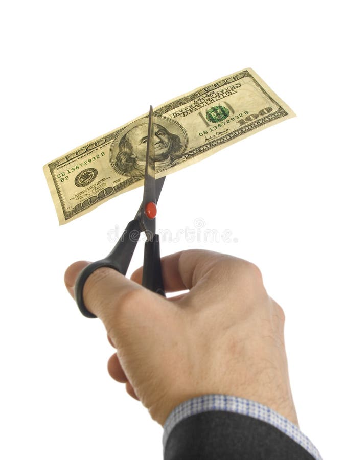 A man's hand cutting a one hundred dollar bill with a pair of scissors. A man's hand cutting a one hundred dollar bill with a pair of scissors.