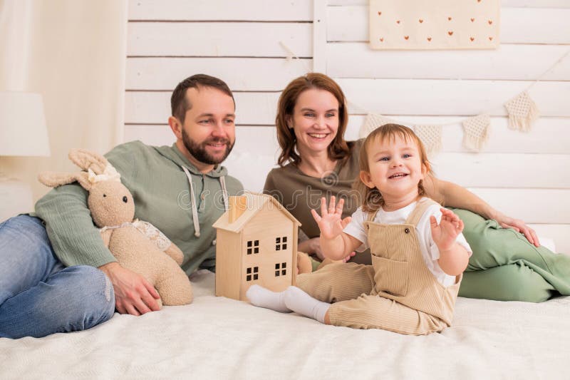 Bimbo allegro gioca su un letto accogliente mentre i loro amanti genitori guardano con sorrisi. fotografia stock libera da diritti