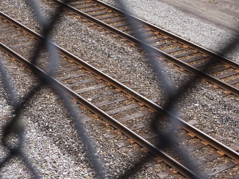 Binari ferroviari di osservazione tramite il recinto del collegamento a catena fotografie stock Binari ferroviari di osservazione tramite il recinto del collegamento a catena fotografie stock