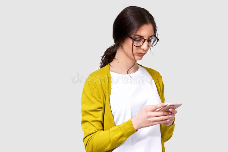 Binnen horizontaal portret van donkerbruine vrij jonge vrouw die cellphone, overseinen aan haar vriend gebruiken stock foto's Binnen horizontaal portret van donkerbruine vrij jonge vrouw die cellphone, overseinen aan haar vriend gebruiken stock foto's