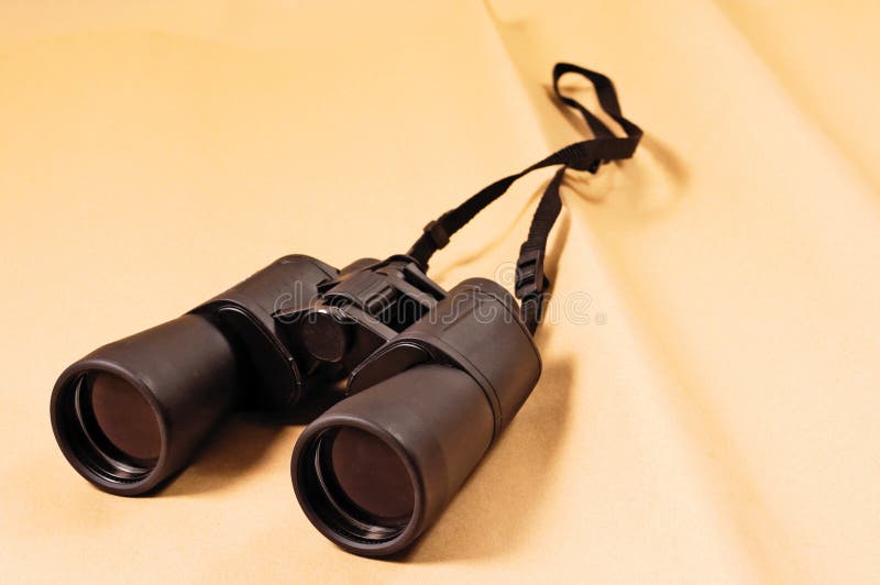 Black binoculars on ancient parchment paper