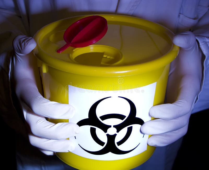 A laboratory worker holding a yellow container with a warning biohazard sign. A laboratory worker holding a yellow container with a warning biohazard sign.