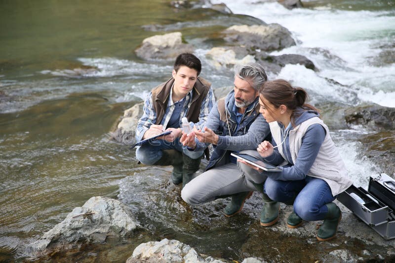 Biologist with students testing river water