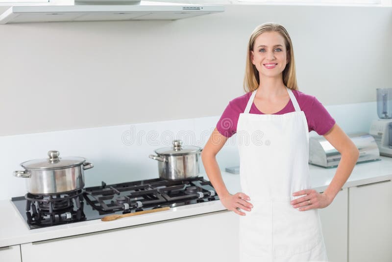Bionda sorridente casuale che sta accanto alla stufa fotografia stock libera da diritti Bionda sorridente casuale che sta accanto alla stufa fotografia stock libera da diritti