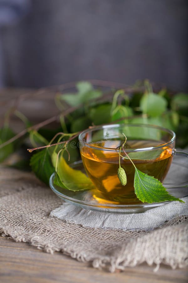 Birch leaf train a glass cup on a wooden surface. royalty free stock photos