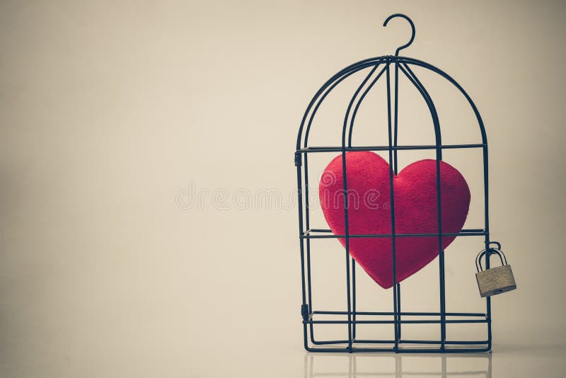 A bird cage with a red heart inside stock photography