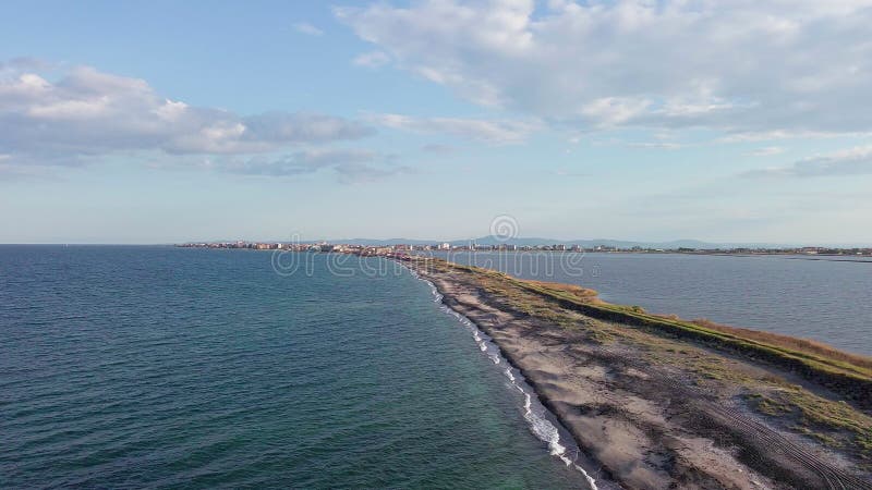 Bird&#x27;s eye view of beach with sand, grass and stones washed by bay of Black Sea and lake under sky in sunset light