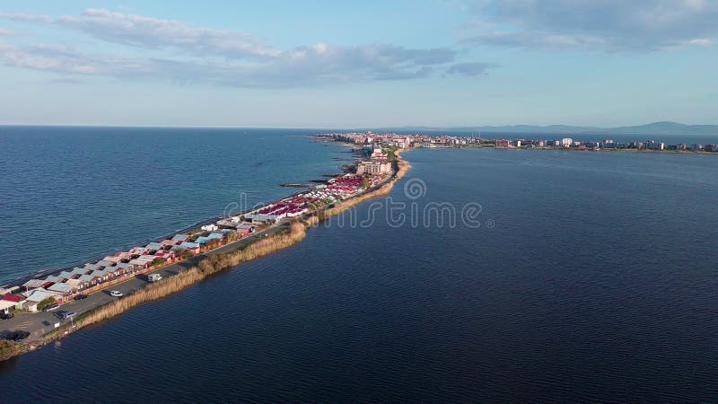 Bird&#x27;s eye view of beach with sand, grass and stones washed by bay of Black Sea and lake under sky in sunset light
