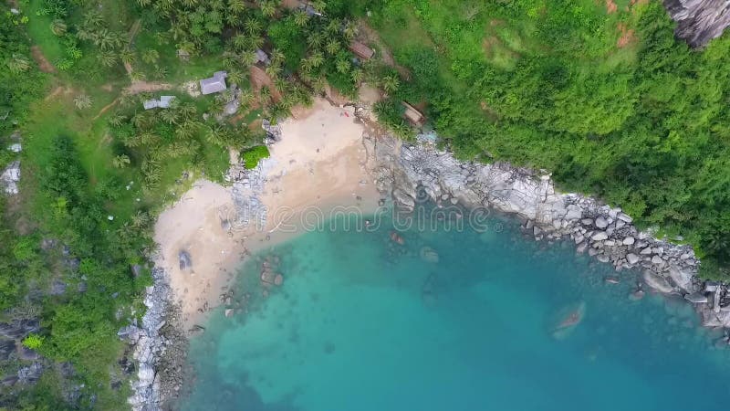 Birds eye view on secret Nui beach with with stones, blue clear water and palm trees. Phuket, Thailand. HD aerial.