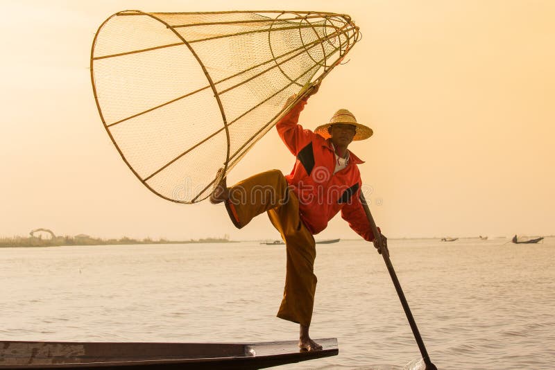 Birmanischer Fischer auf anziehenden Fischen des Bambusbootes auf traditionelle Art mit handgemachtem Netz Inle See, Myanmar (Bir stockbild Birmanischer Fischer auf anziehenden Fischen des Bambusbootes auf traditionelle Art mit handgemachtem Netz Inle See, Myanmar (Bir stockbild