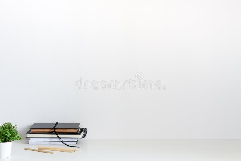 Birou minimalist alb împotriva unui perete alb. copiere spațiu. plantă suculentă și o grămadă de cărți și notebook-uri. stock image