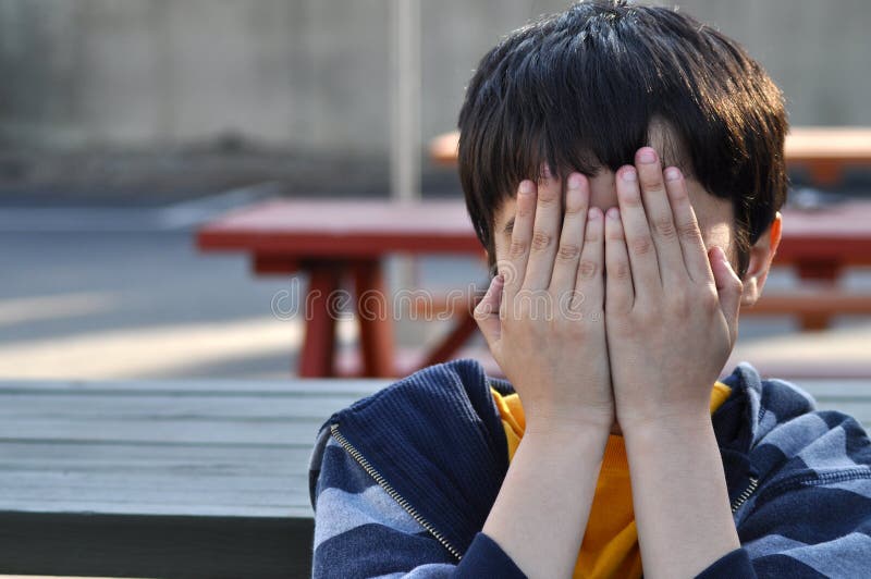 A child throwing a tantrum with hands covering face. Concept of stress, shame, or child abuse. A child throwing a tantrum with hands covering face. Concept of stress, shame, or child abuse.