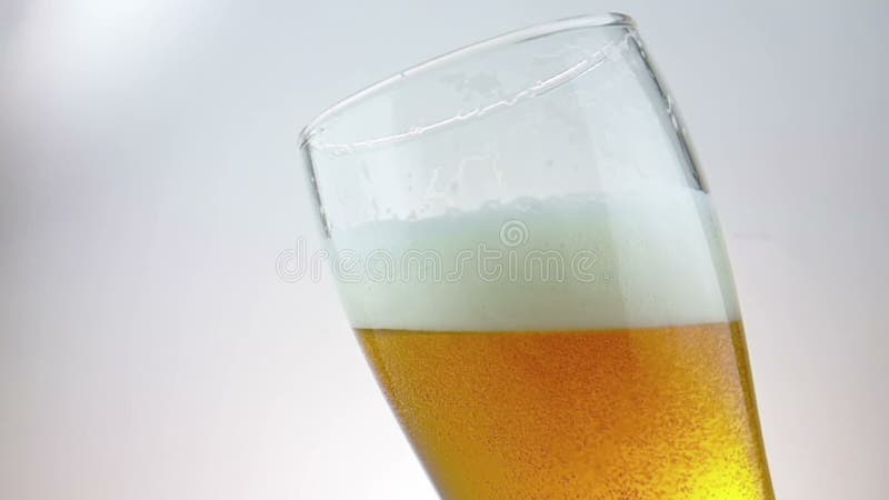 Birra fresca con schiuma nel vetro della pinta della bevanda con le gocce congelate ghiaccio, movimento lento del colpo su fondo