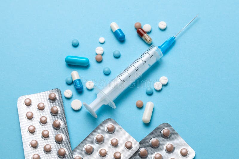 Birth control pills, an injection syringe on blue background