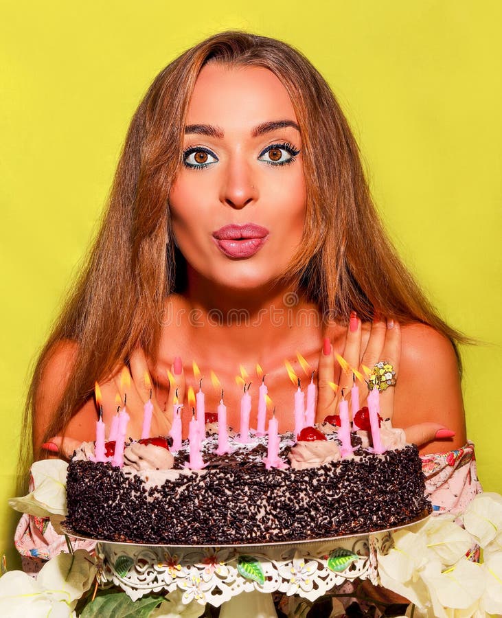 Bella ragazza soffia fuori rosa candele sul cioccolato torta.